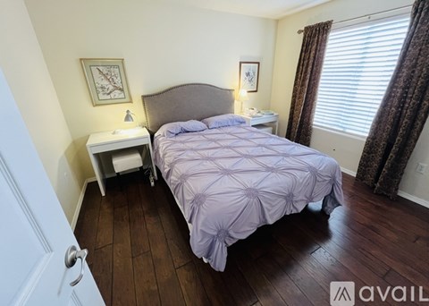 A bedroom with a bed, nightstand, and window.