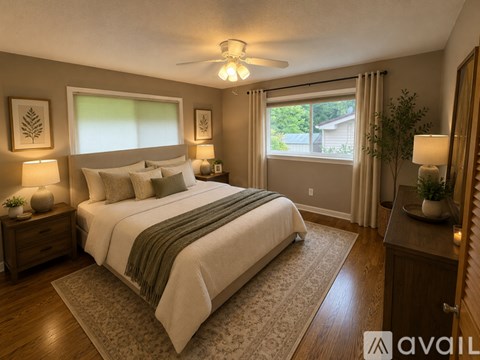 A well-lit bedroom with a large bed and a view of the backyard.