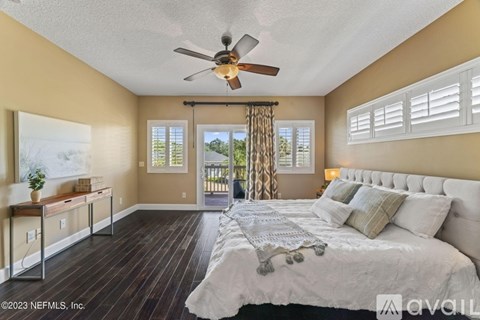 A bedroom with a large bed and a ceiling fan.