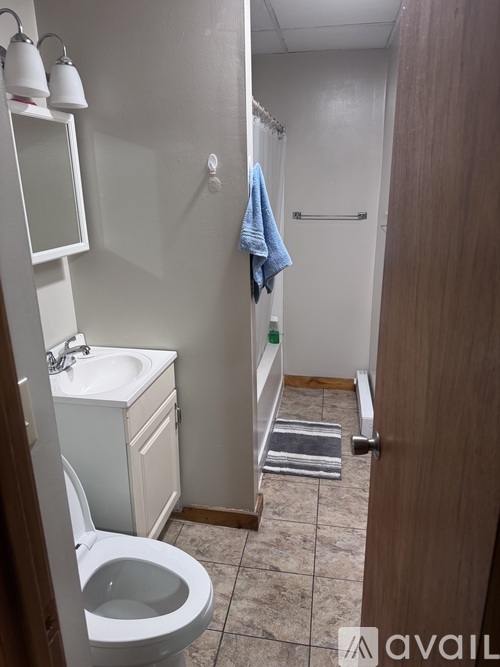 A bathroom with a toilet, sink, mirror, and towel rack.