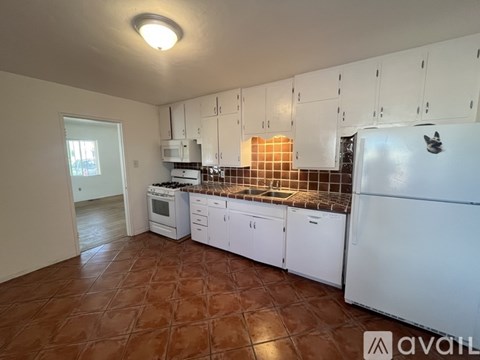 A kitchen with brown tiles and white appliances.