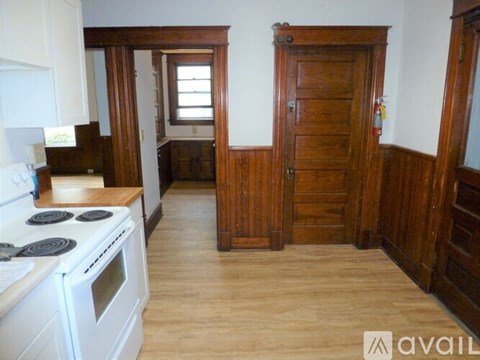 A kitchen with a white stove top oven and wooden floors.