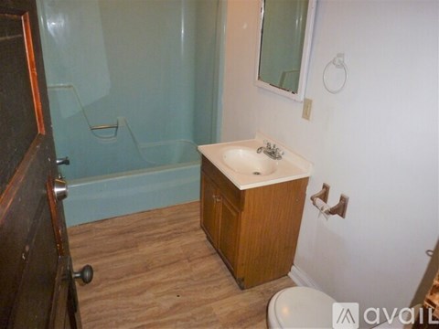 A small bathroom with a wooden vanity and a walk-in shower.