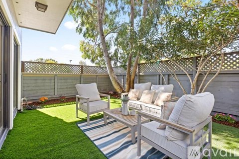 A patio with a white chair and a bench with cushions.