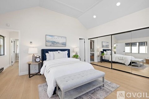 A bedroom with a large bed and a mirrored wall.