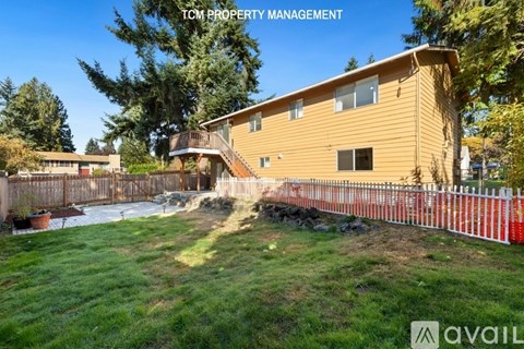 A house with a fence and trees in the background is for sale.