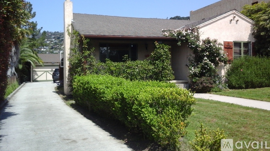 A house with a driveway and green bushes.