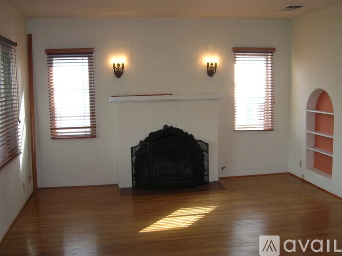 A living room with a fireplace and two windows.