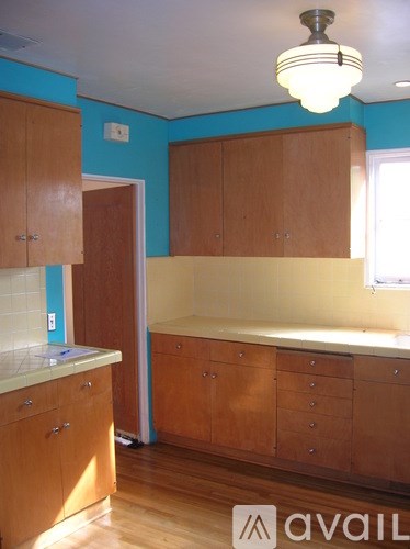 A kitchen with wooden cabinets and a blue wall.