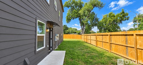 A grey house with a wooden fence and green grass.