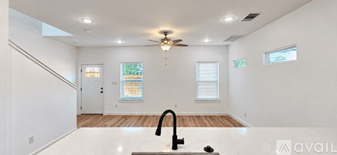 A spacious, empty room with a staircase on the left and a window on the right.