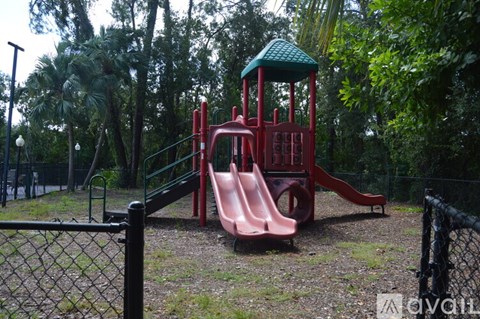 A playground with a red slide and a green roofed tower.