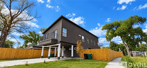 A modern house with a grey exterior and a wooden fence.