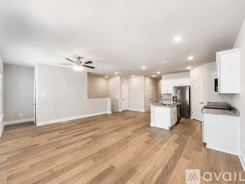 A spacious kitchen with white cabinets and a wooden floor.
