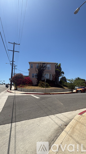 A house with a red flower bush in front of it.