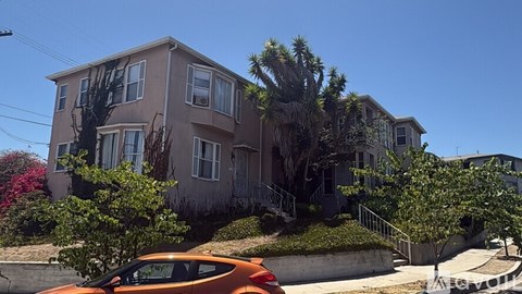 A car is parked in front of a two-story house.
