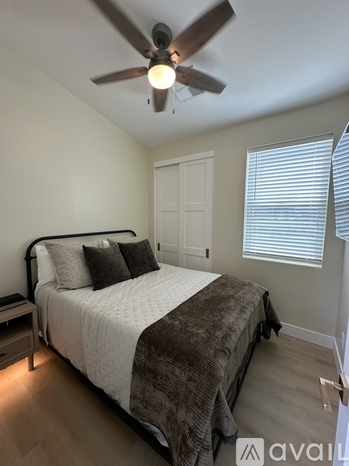A bedroom with a bed, nightstand, and window with blinds.