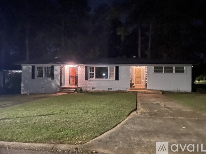 A house with a well-lit front porch is shown at night.