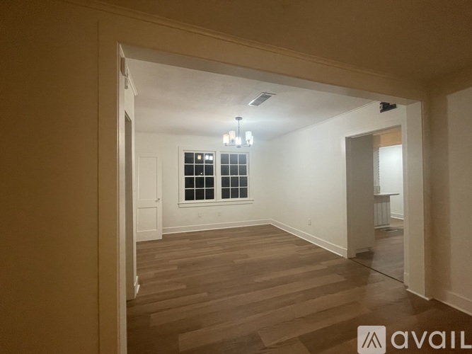 A room with wooden flooring and a window with blinds.