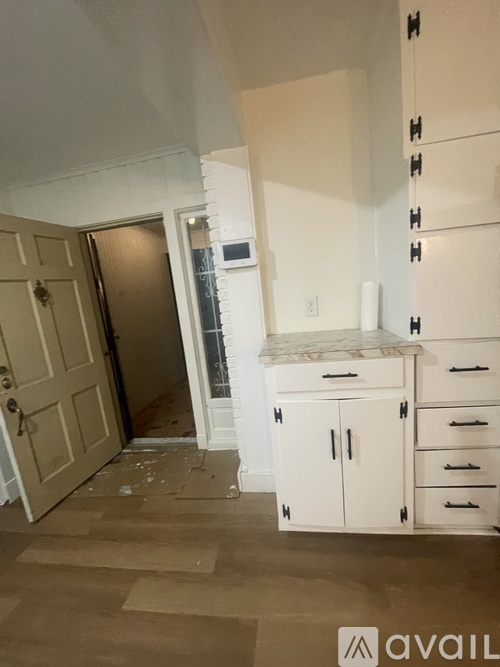 A kitchen with white cabinets and a door open to a hallway.