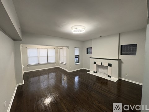 A spacious living room with wood flooring and a fireplace.