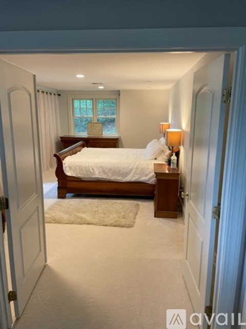 A bedroom with a bed, nightstand, and window.