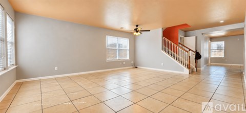 A spacious living room with a tiled floor and a staircase leading to another room.