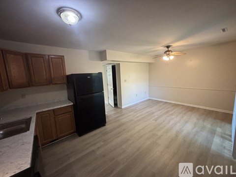 A kitchen with wooden cabinets and a black refrigerator.