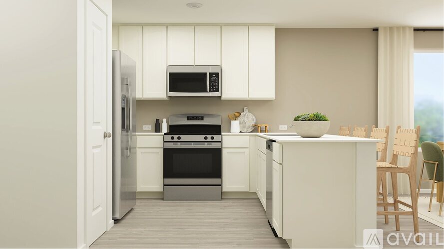 A kitchen with white cabinets and appliances, a wooden floor, and a window with white curtains.