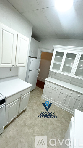 A kitchen with white cabinets and a logo for Vodock Apartments.