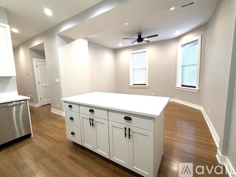 A kitchen with white cabinets and a wooden floor.