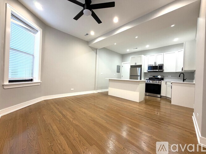 A spacious kitchen and living room with wooden flooring and white walls.
