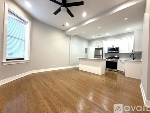 A spacious kitchen and living room with wooden flooring and white walls.