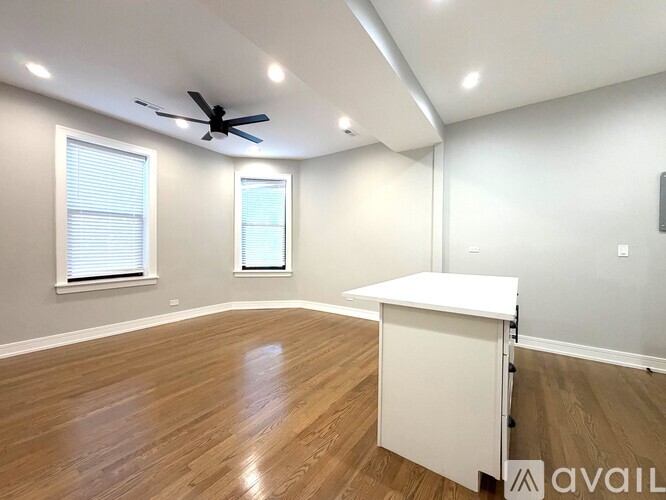 A room with a ceiling fan and wooden flooring.