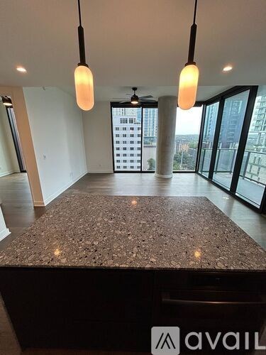 A spacious room with a granite countertop and pendant lights.