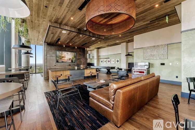 A modern living room with a brown leather couch and a wooden ceiling.