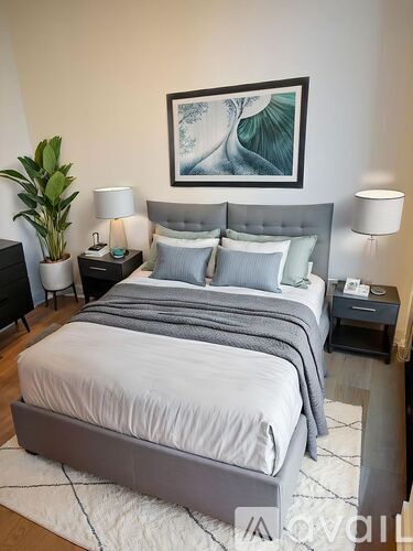 A bedroom with a large bed and a painting on the wall.