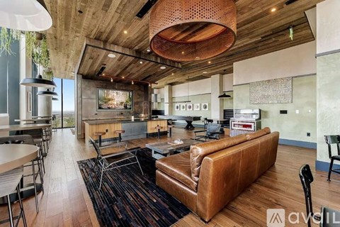 A modern living room with a brown leather couch and a wooden ceiling.