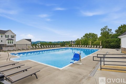 A large outdoor swimming pool with a blue lounge chair and a black fence.
