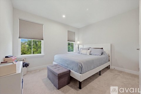 A bedroom with a large bed and a window with blinds.