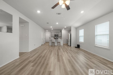 A spacious living room with a ceiling fan and lighting fixtures.