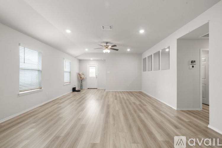 A spacious room with wooden flooring and a ceiling fan.