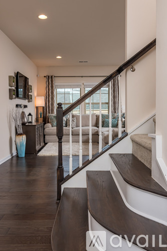 A staircase with a wooden handrail and a white wall.