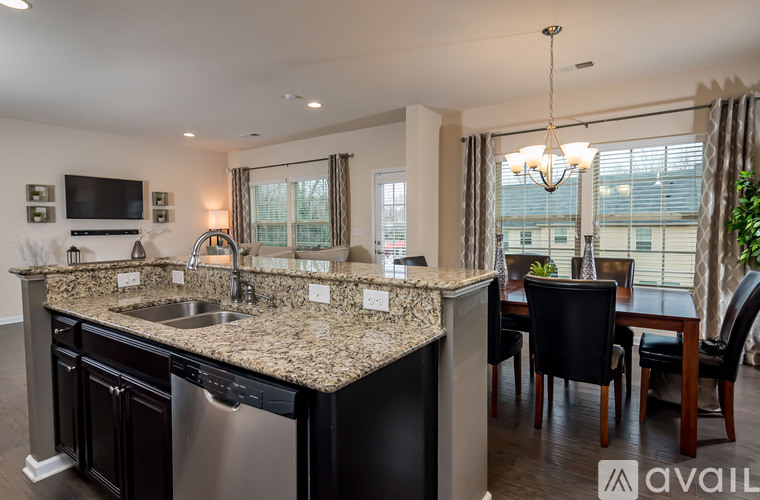 A kitchen with granite countertops and a dining area with a table and chairs.
