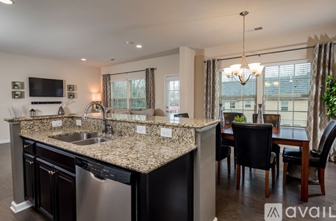 A kitchen with granite countertops and a dining area with a table and chairs.