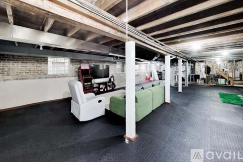 A spacious room with a green sofa and a television.