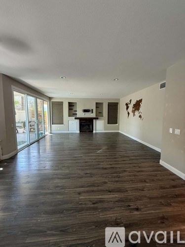 A spacious living room with wood flooring and a fireplace.