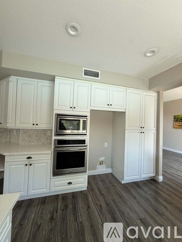 A kitchen with white cabinets and a wooden floor.