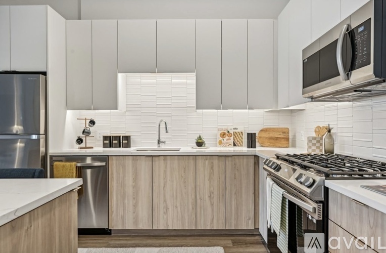 A modern kitchen with a stainless steel refrigerator, a white countertop, and wooden cabinets.