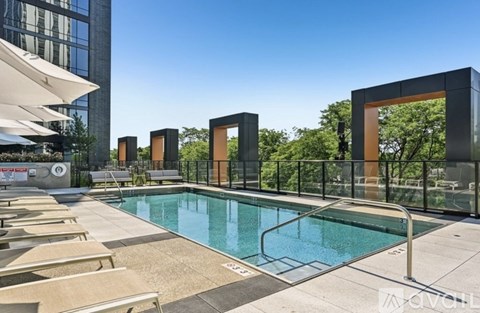 A pool surrounded by sun loungers and a glass railing.
